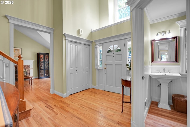 entrance foyer featuring light wood-style floors, stairs, crown molding, and a high ceiling