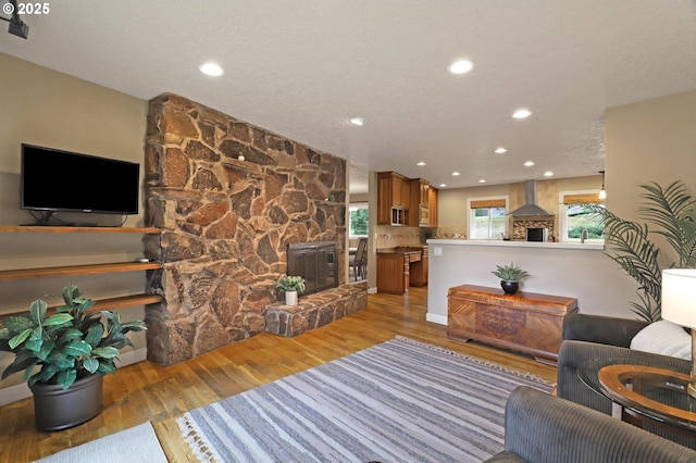 living area featuring a textured ceiling, light wood-type flooring, a fireplace, and recessed lighting