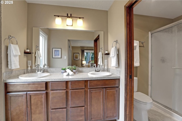 bathroom featuring double vanity, a sink, toilet, and a shower stall