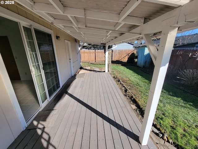 wooden terrace featuring a fenced backyard and a lawn