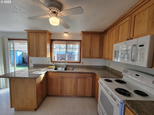 kitchen featuring a peninsula, white appliances, a sink, and a healthy amount of sunlight