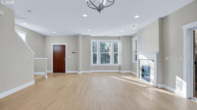 unfurnished living room with light wood-type flooring, a tiled fireplace, and recessed lighting