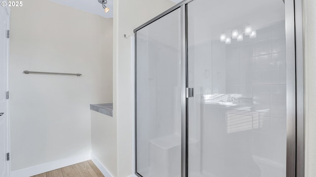 bathroom with a shower stall, baseboards, and wood finished floors