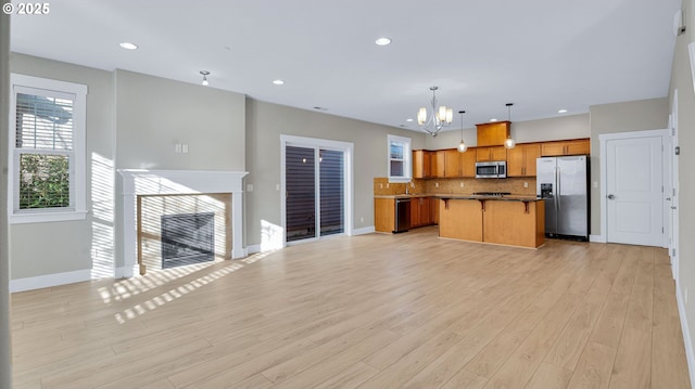 kitchen with tasteful backsplash, appliances with stainless steel finishes, open floor plan, a kitchen island, and a tile fireplace