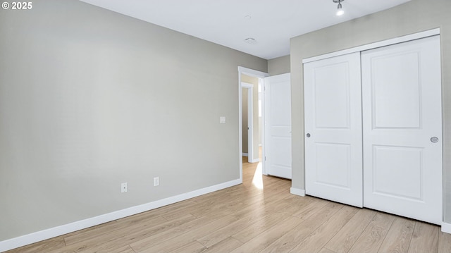 unfurnished bedroom with baseboards, a closet, and light wood-style floors