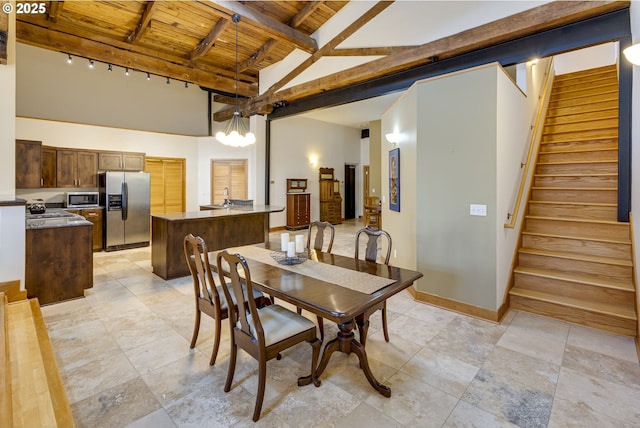 dining area featuring beam ceiling, high vaulted ceiling, wooden ceiling, baseboards, and stairs