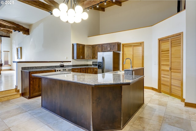 kitchen with a notable chandelier, a peninsula, a sink, a towering ceiling, and appliances with stainless steel finishes