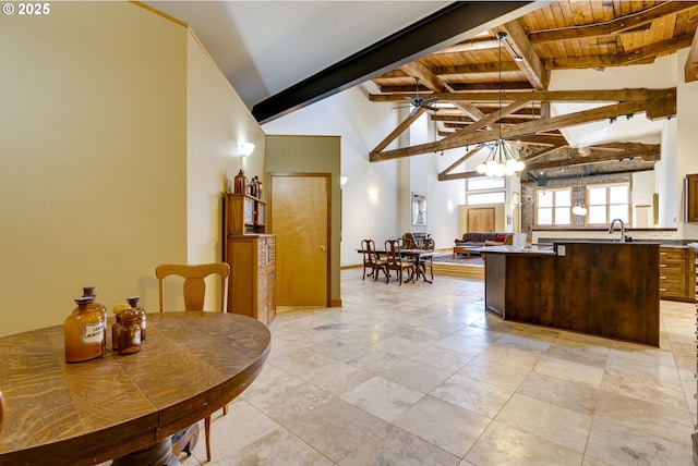 kitchen featuring ceiling fan with notable chandelier, a sink, wood ceiling, open floor plan, and beam ceiling