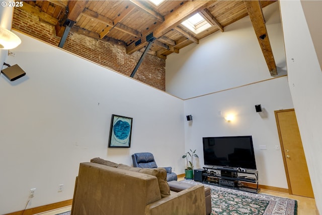 living area with a skylight, beam ceiling, a towering ceiling, wood ceiling, and baseboards