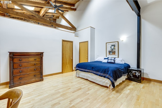 bedroom with wood finished floors, beam ceiling, and baseboards