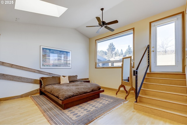 sitting room featuring baseboards, lofted ceiling with skylight, ceiling fan, stairway, and wood finished floors