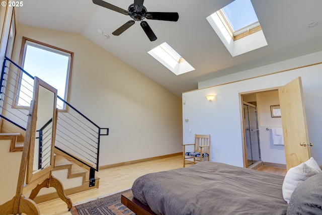 bedroom featuring ceiling fan, wood finished floors, baseboards, vaulted ceiling, and ensuite bath