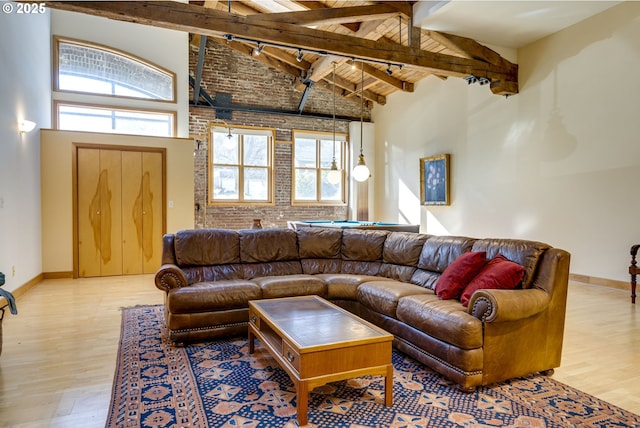 living area featuring high vaulted ceiling, light wood finished floors, plenty of natural light, and beam ceiling