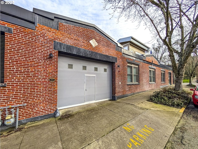 view of home's exterior with driveway, brick siding, and an attached garage