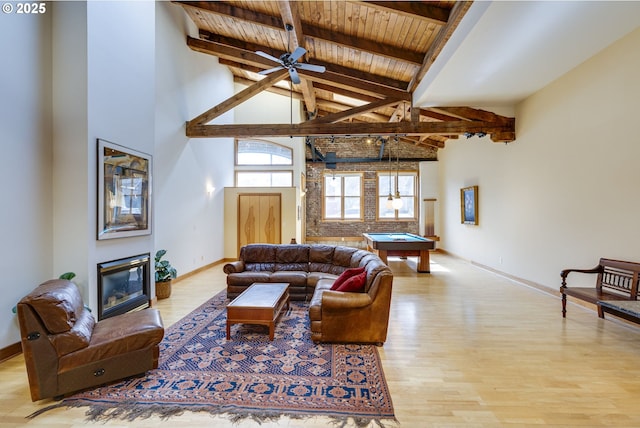 living room featuring beamed ceiling, a glass covered fireplace, wood ceiling, wood finished floors, and billiards