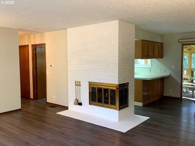 unfurnished living room featuring dark wood-type flooring, a fireplace, and a textured ceiling