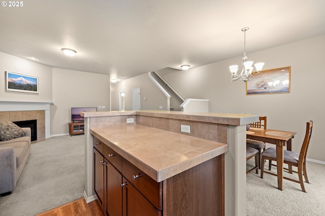 kitchen with tile counters, a tile fireplace, open floor plan, and light colored carpet