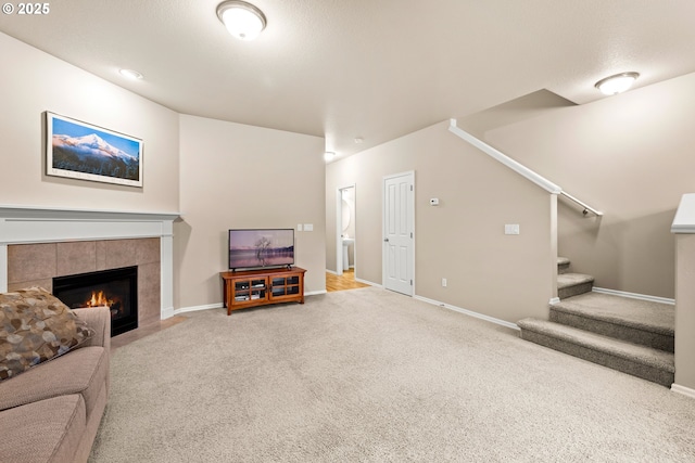 living area with carpet, a fireplace, stairway, and baseboards