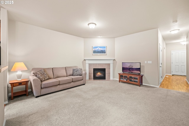 living area with carpet floors, a tiled fireplace, and baseboards