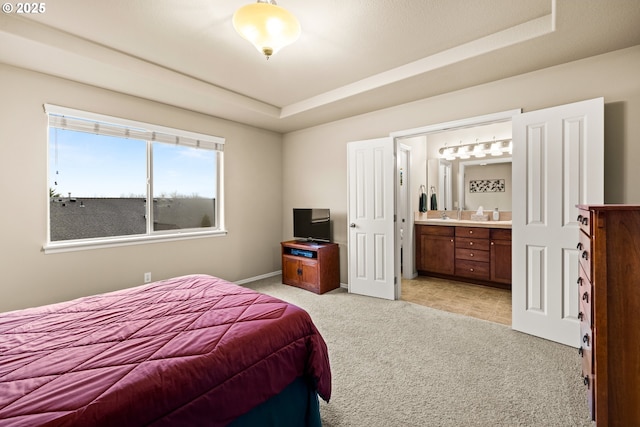 bedroom featuring baseboards, a tray ceiling, connected bathroom, and light colored carpet