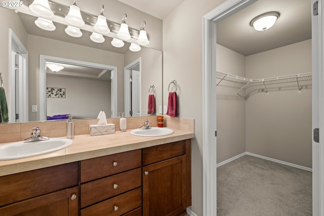 full bath featuring a sink, a spacious closet, baseboards, and double vanity
