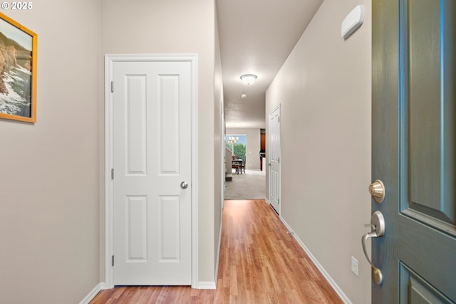 hallway featuring baseboards and light wood-style floors