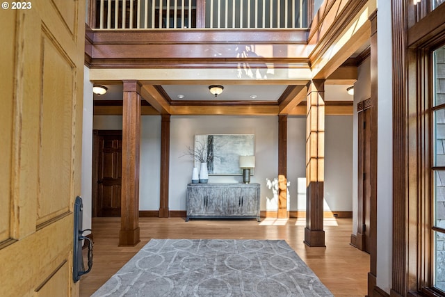 interior space with baseboards, crown molding, ornate columns, and wood finished floors