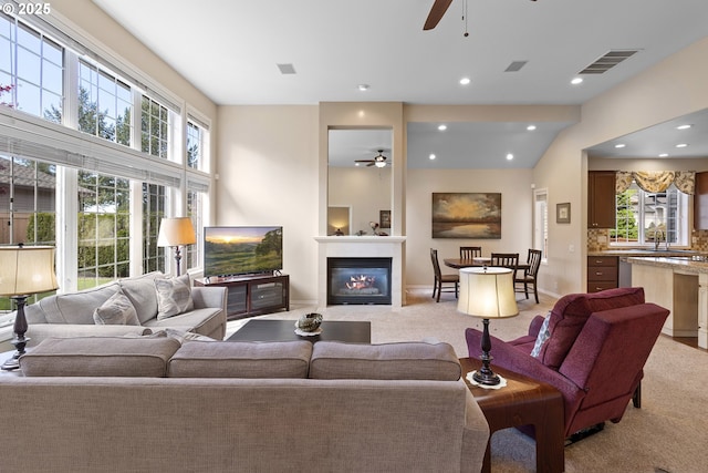 living area with visible vents, a glass covered fireplace, ceiling fan, light colored carpet, and recessed lighting