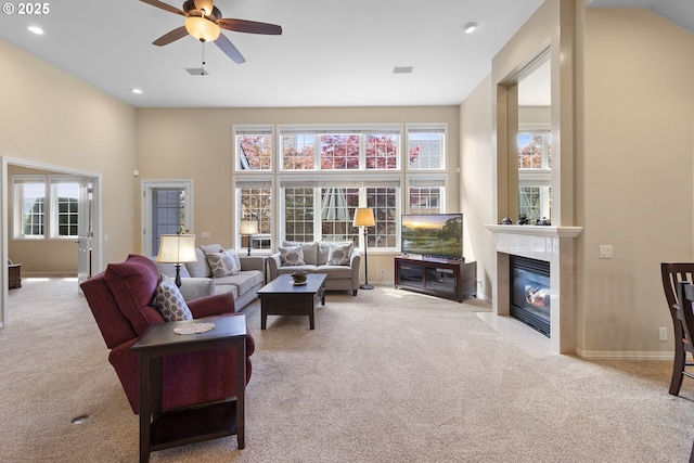 living room with carpet floors, a ceiling fan, a fireplace with flush hearth, and a wealth of natural light