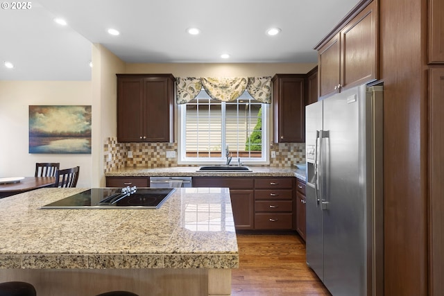 kitchen featuring decorative backsplash, wood finished floors, recessed lighting, a sink, and stainless steel appliances