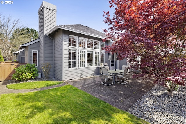 back of property featuring a lawn, a patio area, fence, and a chimney