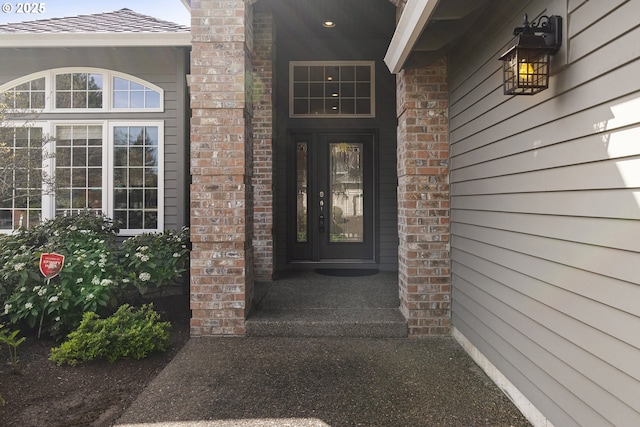 doorway to property featuring a porch and a shingled roof