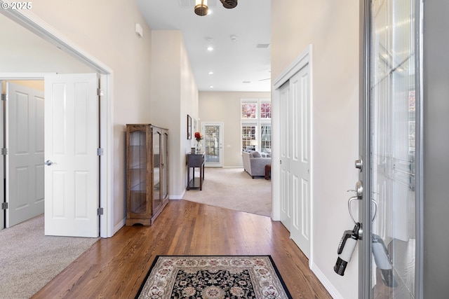 foyer featuring baseboards, carpet floors, recessed lighting, and wood finished floors