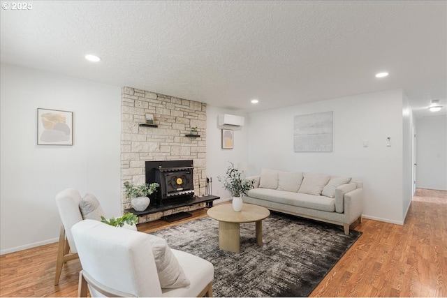 3434 Memorial Park Dr, Longview, WA 98632 - living room featuring a wall mounted air conditioner, a textured ceiling, wood finished floors, recessed lighting, and a wood stove