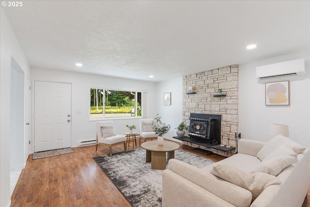3434 Memorial Park Dr, Longview, WA 98632 - living room featuring an AC wall unit, a baseboard radiator, wood finished floors, recessed lighting, and a textured ceiling