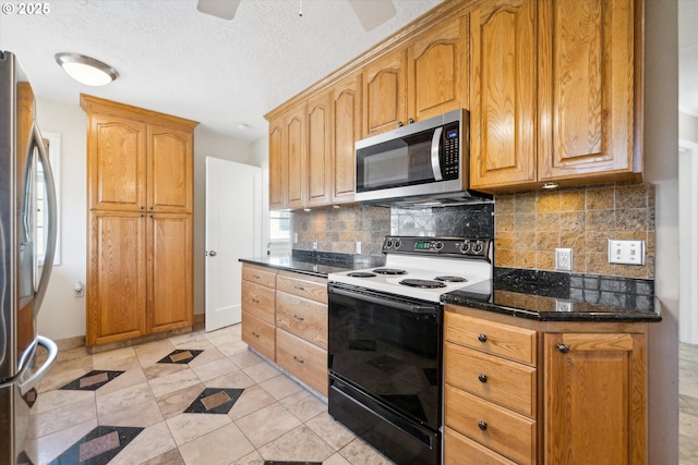 kitchen with ceiling fan, dark stone countertops, stainless steel appliances, a textured ceiling, and backsplash