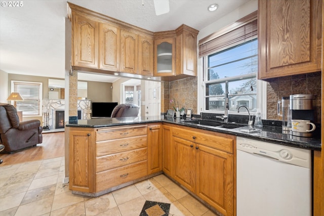 kitchen with open floor plan, a fireplace, dishwasher, and a sink