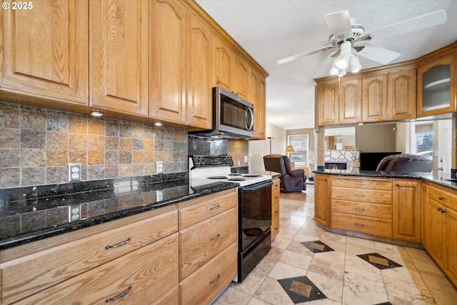 kitchen with electric stove, tasteful backsplash, stainless steel microwave, a ceiling fan, and dark stone counters