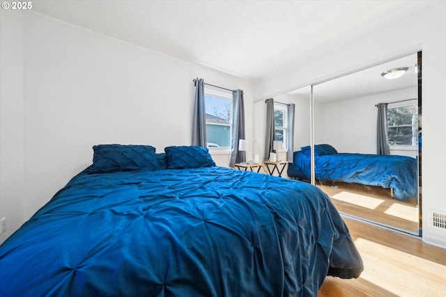 bedroom with a closet, visible vents, and wood finished floors