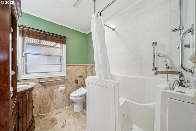 bathroom with a wainscoted wall, tile walls, toilet, ornamental molding, and vanity