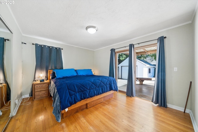 bedroom featuring crown molding, light wood finished floors, a textured ceiling, access to outside, and baseboards