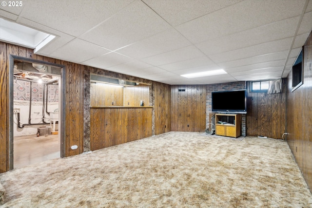 below grade area featuring wood walls, carpet flooring, and a paneled ceiling