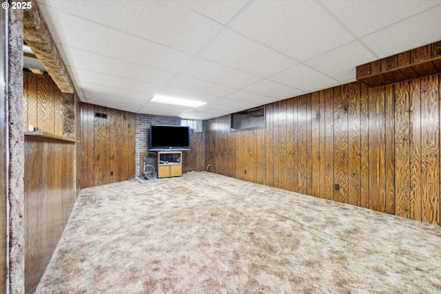 finished below grade area with a paneled ceiling, wood walls, and carpet