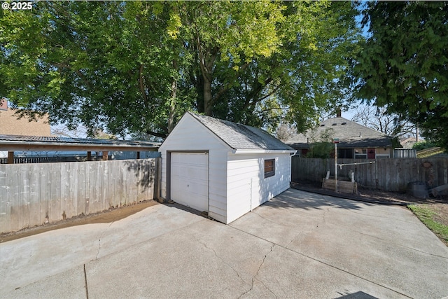 detached garage featuring driveway and fence