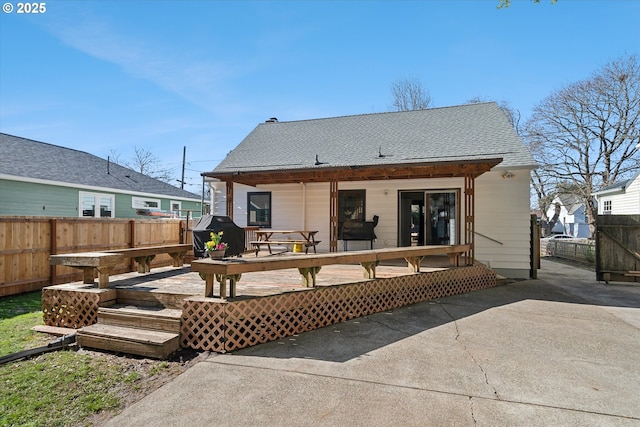 back of property featuring roof with shingles, fence, and a wooden deck