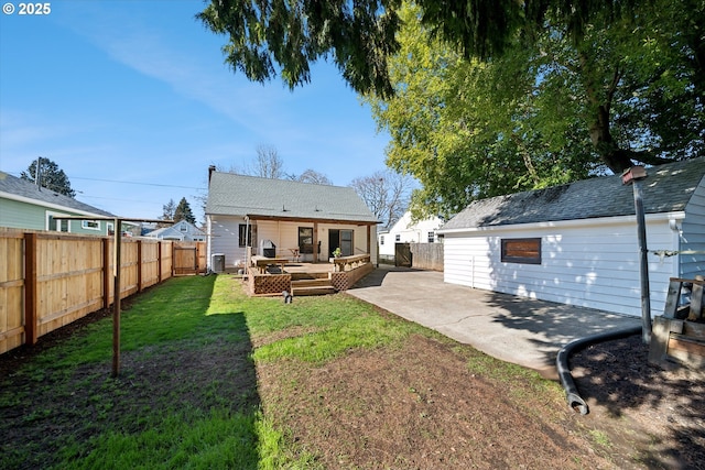 back of house featuring a fenced backyard, a yard, a wooden deck, and a patio