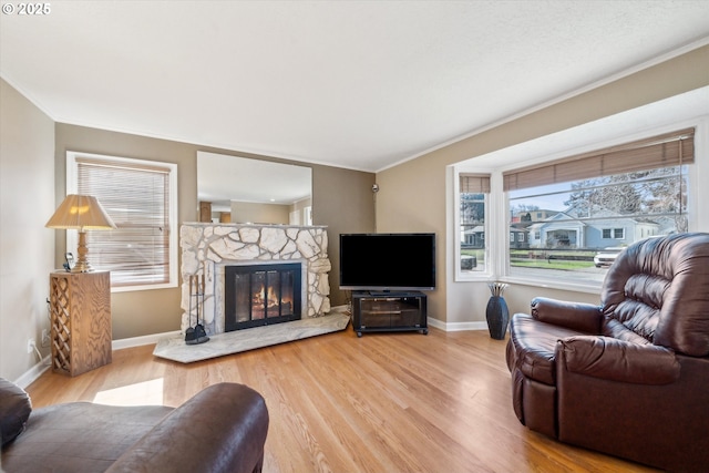 living room featuring a stone fireplace, ornamental molding, and wood finished floors