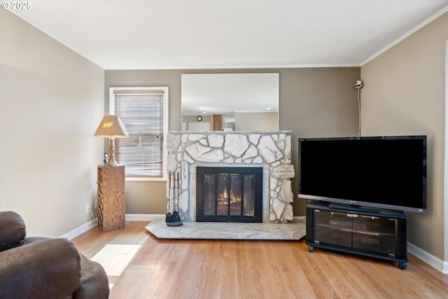 living room featuring baseboards, a fireplace, wood finished floors, and crown molding