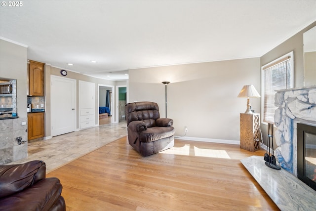 living area with ornamental molding, a fireplace, recessed lighting, and baseboards