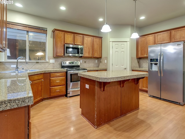 18840 SW Westland Ln, Beaverton, OR 97003 - kitchen with stainless steel appliances, light wood-style flooring, brown cabinets, tasteful backsplash, and a kitchen breakfast bar